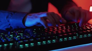 Serbest bir iş. Bilgisayar programlama. Tanımlanamayan erkek elleri dikişsiz döngü sohbetleri klavye mesajlaşması ile koyu neon rengi ışık oyununda oyun oynuyorlar..