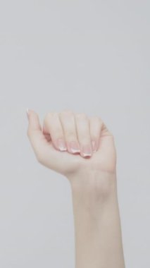 Dikey video. Güle güle jest. Güle güle işareti. Kadın, arka planda parmaklarını hızla büküyor..