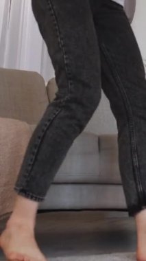 Dikey video. Evde rahatla. Mutlu kadın. Dinlenmenin tadını çıkarıyorum. Tatmin olmuş, gülümseyen kız rahat bir koltukta oturuyor, kollarını açık bir odada açıyor..