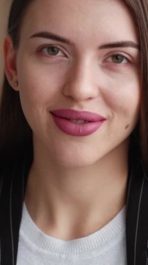 Dikey video. İş kadını. Zarif bir görünüş. Ofis tarzı. Gülümseyen, kendine güvenen, çenesine dokunan başarılı bir bayan..
