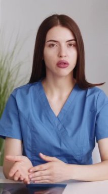 Dikey video. Kadın bir doktor. Tıbbi danışmanlık. Ciddi kadın hemşire, iç mekanda viral hastalıkların önlenmesinden bahsediyor..