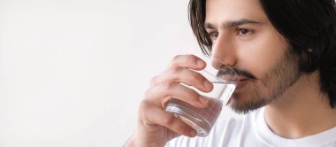 İçme suyu. Sıvı dengesi. Yakışıklı adam beyaz fotokopi arkaplanında izole edilmiş temiz içecekten zevk alıyor..