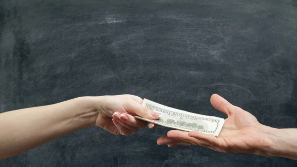 Money loan. Financial support. Man and woman hands holding dollars on chalkboard background.