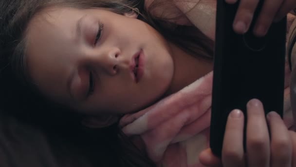 垂直录像 孩子们失眠 夜间电影 睡觉时间到了疲惫困倦的小女孩在黑暗的卧室里通过电话看电影 — 图库视频影像