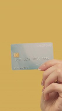 Dikey video. Para transferi. Nakit ödeme. Sarı arka planda dolarları olan el yiyen bir kadın..