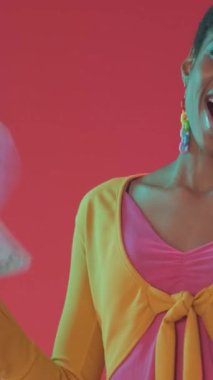 Dikey video. Milyoner parası. Piyango kazandı. Finansal ödül. Mutlu, mutlu, gülümseyen, zengin bir kadın dolar sallıyor. Pembe renkli neon ışıkta para hayranı..