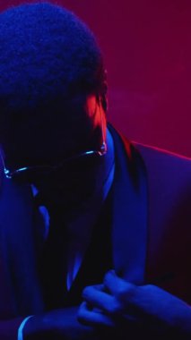 Dikey video. Milyoner parası. Piyango talihlisi. Finansal ödül. Mavi pembe neon ışık tatmin olmuş gülümseyen zengin iş adamı dolar para yelpazesi sallıyor..