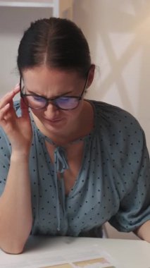 Dikey video. İş stresi. Profesyonel baş ağrısı. Aşırı çalışma yorgunluğu. Migren krizi geçiren yorgun kadın çalışan iş yerindeki şakaklara masaj yapıyor..