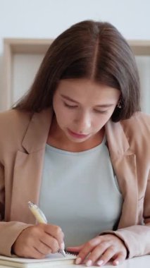 Dikey video. Online danışmanlık. İnternet toplantısı. Akıl hocası aradı. Heyecanlı, güler yüzlü, takım elbiseli bir kadın not yazıyor..