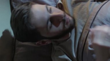 Dikey video. Gece endişesi. Uyku bozukluğu. Panik atak. Korkmuş bir adam, karanlık bir yatak odasında kâbusla uyanır..