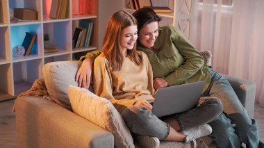 Koltuk bakınıyor. Aile ağları. Gülümseyen genç kız film izliyor İnternet 'te sörf yapıyor kanepede oturuyor..