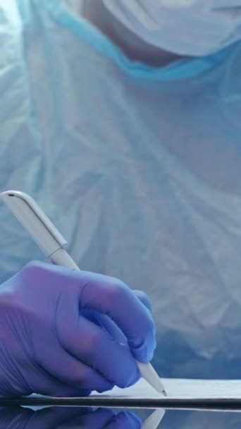 垂直ビデオ 医学的評価 コロナウイルスのパンデミック 青い医療用ゴム手袋で手でレポートを書く保護装置の医師 — ストック動画