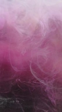 Dikey video. Mürekkep damlası. Renkli duman sıçraması. Fantezi patlaması. Pastel pembe buhar bulutu koyu siyah simli toz parçacıkları üzerinde yüzüyor soyut sanat arka planı.