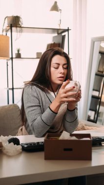 Hasta hissediyorum. Grip salgını. Ofis hastalığı. Battaniyeli, elinde sıcak içecek bardağıyla klavyeli ve hafif mendilli bir kız..