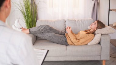 Terapi seansı. Psikolog ofisi. Mutsuz genç kız hayatı şikayet ediyor psikoterapi terapisinde kanepe uzanıyor..