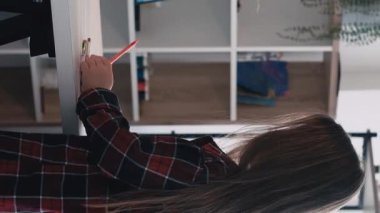 Dikey video. Sanat okulu. Çocuklar resim yapıyor. Sanatsal ders. Çizim odası için renkli kalemleri olan küçük bir kız oturuyor..