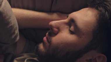 Dikey video. Gece terörü. Uyku bozukluğu. Kötü bir rüya. Huzursuz korkmuş bir adam, karanlık yatak odasında kabustan uyanıyor..