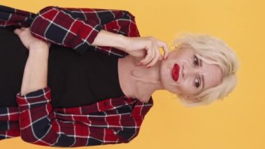 Dikey video. Şüpheci kadın. Belirsiz fikirler. Gülünç bir durum. Şüpheli orta yaşlı bayan sarı poz vermeyi düşünüyor..