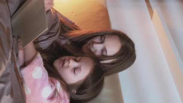 垂直录像 儿童阅读 家庭之夜 睡觉前学习 松懈的母亲小女儿在卧室的床上谈论着书的故事 — 图库视频影像