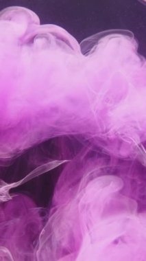 Dikey video. Boya suyu sıçraması. Renkli duman bulutu. Geçiş efekti. Pembe duman patlama dalgası, koyu mor parıltı dokusu soyut sanat arka planında.