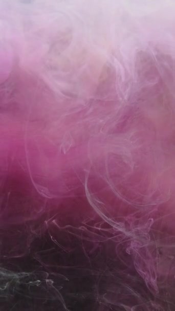 垂直ビデオ インクの水が落ちる 色の煙スプラッシュ 幻想的な爆発 ダークブラックの輝きに浮かぶパステルピンクの蒸気雲ダスト粒子アブストラクトアート背景 — ストック動画
