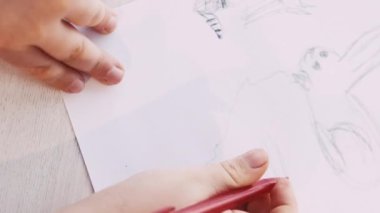 Dikey video. Güzel resim. Çocuklar resim yapıyor. Sanat hobisi. Beyaz kağıda kalem oturma masası çizen tanınmamış bir çocuk..