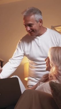 Dikey video. Aile online akşamı. Ev ağları. Neşeli baba, kızını ve eşini kucaklıyor dizüstü bilgisayarda ev içi kanepe oturma programını tartışıyor..