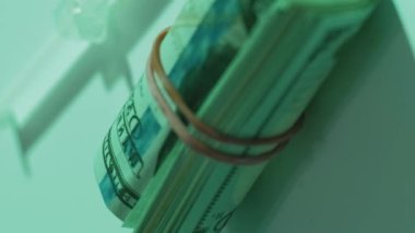 Eczane kârı. Uyuşturucu bağımlılığı. Madde bağımlılığı. İlaç masrafı. ABD Doları para rulosu beyaz yüzey dikey video üzerinde şırınga hapları doldurdu.
