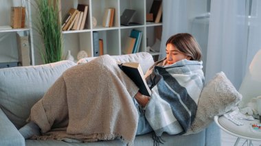 Samimi bir kitap. Ev tatili. Hasta kadın dinleniyor. İlginç bir romandan keyif alıyor. Ekoseye sarılmış, açık renkli bir iç kanepede oturuyor..