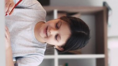 Dikey video. Sanat okulu. Mutlu küçük kız. Hobi olarak. Gülümseyen kadın çocuk stüdyo içinde kağıt üzerine çizim yapmaktan zevk alıyor..