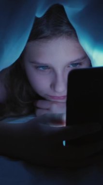 Dikey video. Akıllı telefon çocukluğu. Gece sörfü. İnternet takıntısı. Uykusuzluktan sıkılmış uykusuz bir kız. Yorganın altına saklanıp evde saklanıyor..