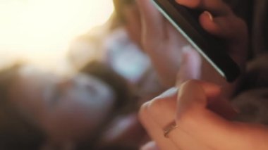 Dikey video. Ebeveyn sohbeti geçmişi bulanık. Mobil iletişim. Çocuk anne, kullanılamayan boş alan üzerindeki telefon uygulamasını kullanarak çevrimiçi mesaj gönderiyor.
