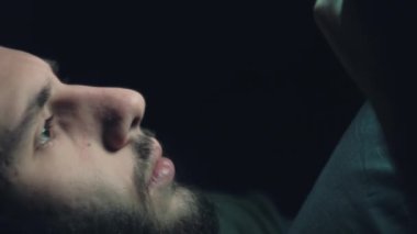 Dikey video. Film gecesi. Gadget 'ın boş vakti. İnternette geç kaldım. Meraklı, şaşırmış bir adam elektronik cihazda gerilim filmi seyrediyor. Işıklar yanıp sönüyor, karanlık boşlukta..