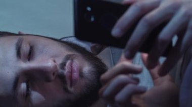 Dikey video. Gece sohbeti. Gadget uykusuzluğu. Çevrimiçi iletişim. Akşamları akıllı telefondan mesaj atan bıkkın bir adam..