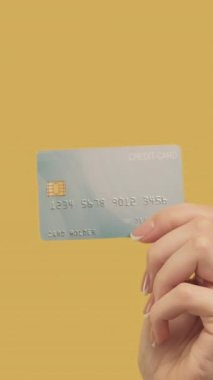 Dikey video. Para transferi. Nakit ödeme. Sarı arka planda dolarları olan el yiyen bir kadın..