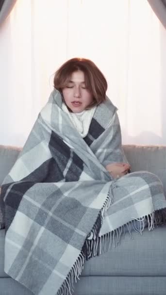 垂直录像 病得浑身哆嗦 抱着感冒的女人裹着毛毯温热感冒症状坐在家里的沙发上感觉不舒服 — 图库视频影像
