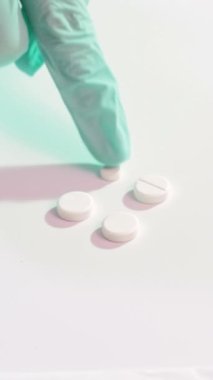 Dikey video. Eczacılık tedavisi için. Kombinasyon terapisi. İlaç tedavisi için. Doktor, beyaz yüzeydeki ilaç sayma eldivenlerini getirdi..