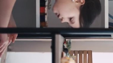 Dikey video. Resim okulunda. İlham verici bir kız. Sanatsal aletler. Işık stüdyosunun içinde çizim yapmak için sanat eserlerini seçen mutlu kadın çocuk..