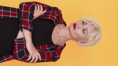 Dikey video. Hayal kırıklığına uğradım. Üzgün kadın. Üzücü duygular. Üzgün orta yaşlı bir kadın kederini dile getiriyor. Sarı göğüste el ele tutuşuyor..