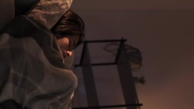 Dikey video. Uyku bozukluğu. Gece endişesi. Stres uykusuzluğu. Huzursuz, yorgun bir adam karanlık bir evde rahatsız bir kanepede uyanıyor..