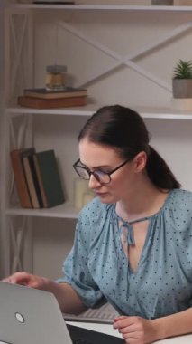 Dikey video. İş stresi. Profesyonel patinaj. Bağımsız yaşam tarzı. Huzursuz kadın çalışan ev işyerinde içki içerek bilgisayarını kapatıyor..