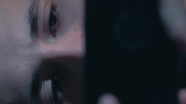 Dikey video. Çevrimiçi korku. Gece filmi. Gadget akşamı. Endişeli, korkmuş adam suratıyla telefonda dramatik gerilim dizisini izliyor..