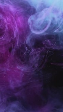 Dikey video. Renkli duman bulutu. Mürekkep suyu karışımı. Fantezi dalgası. Neon mavisi parlak toz parçacıkları koyu siyah soyut sanat arka planında hareket sıçratır.