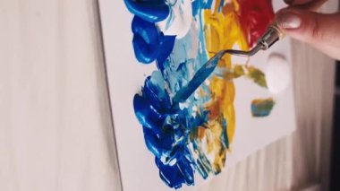 Dikey video. Sanat süreci. Kadın ressam. Resim okulunda. Resim odası yaratmak için spatulayla boyaları karıştıran tanınmamış bir kadın..