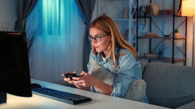 Oyun bağımlılığı. Rekabetçi kadın. Dijital teknoloji. Bilgisayarda konsolla oynayan esinlenilmiş kadın koltukta oturuyor..