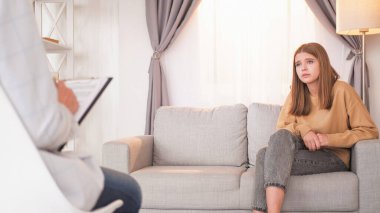 Psikoterapi seansı. Akıl sağlığı. Sinirli genç kız, psikolog aydınlatma odasının iç mekânına danışmak için koltukta oturuyor..