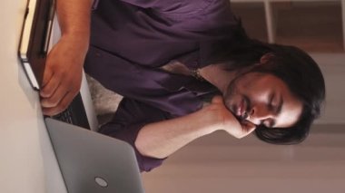 Dikey video. Yorgunluğa çalış. Evde e-öğrenim. Uzaktan eğitim. Yorgun, uykulu adam dizüstü bilgisayardan sanal ders izlerken uyuyakalıyor..
