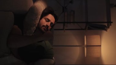 Dikey video. Huzursuz bir gece. Uykusuzluk sorunu. Zihinsel aşırı yüklenme. Üzgün, düşünceli, düşünceli bir adam geç saatlere kadar kanepede uzanıyor..