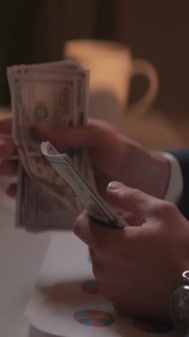 Dikey video. İş gelirleri. Erkek şef. Finansal bütçe. Tanınmayacak kadar zengin bir adam. Paraları sayıyor. Loş ışık odasının içinde oturuyor..