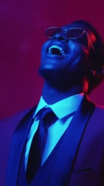 Dikey video. Büyük ikramiye. Başarı kutlaması. Finansal şans. Mavi pembe neon ışığı, gülen zengin adamın para harcayıp renkli dumana para saçmasından memnun..